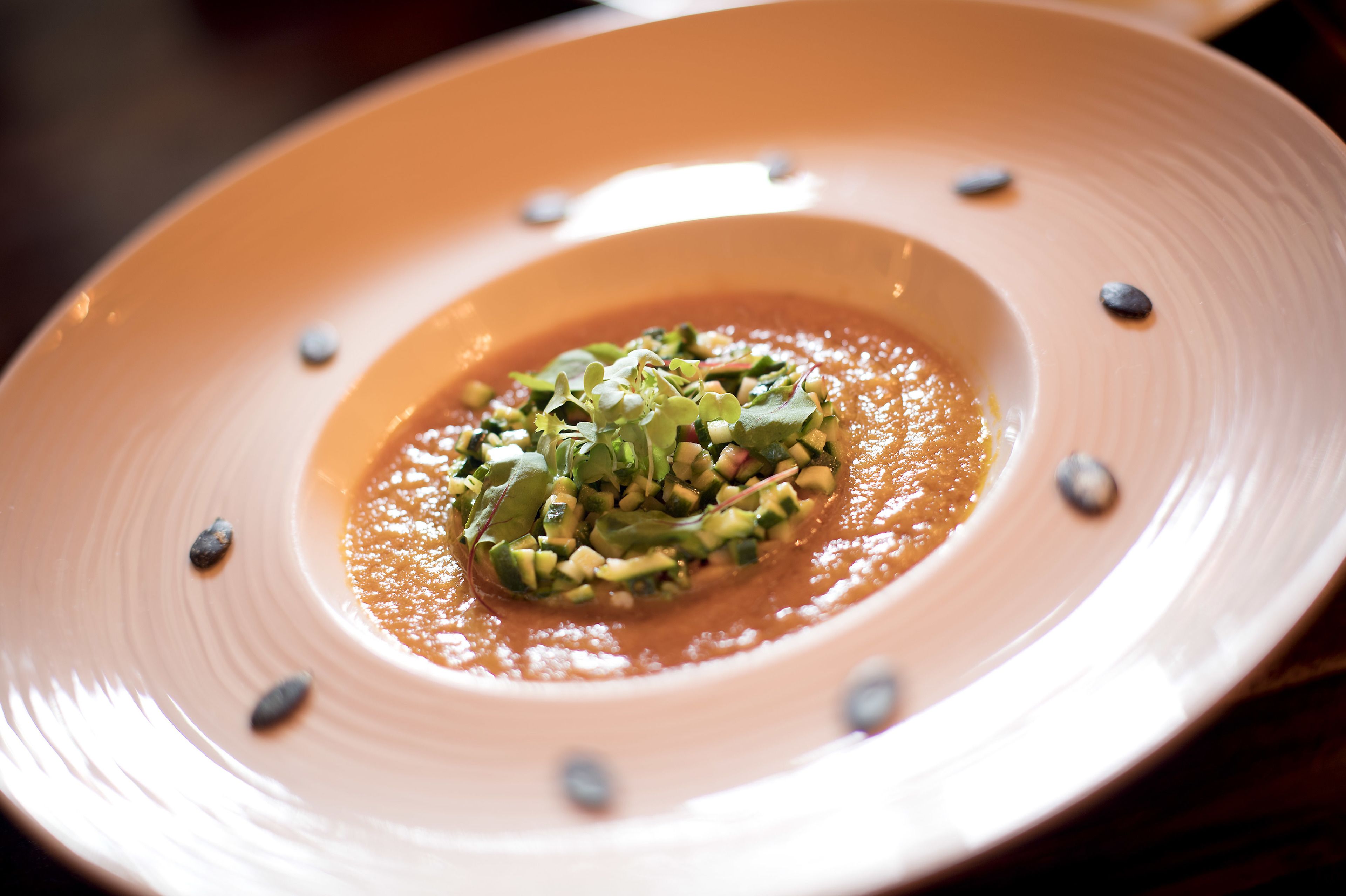 Une assiette de nourriture composée d’une base crémeuse, agrémentée de légumes verts et de légumes coupés en dés.
