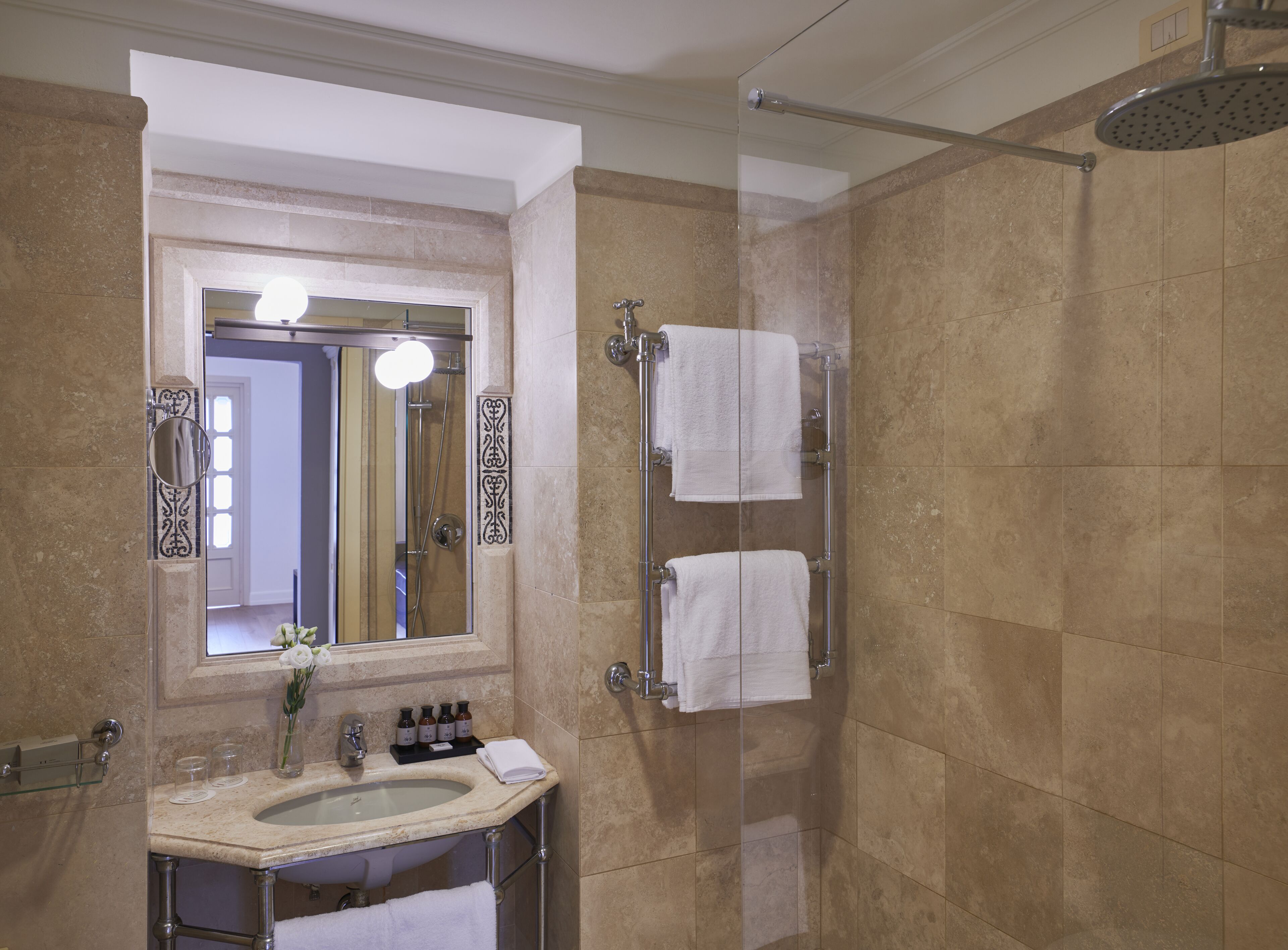 A bathroom with a sink, mirror, and shower.