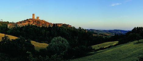 A historic town with a prominent tower, surrounded by lush greenery and rolling hills.