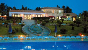 Un grand bâtiment en pierre doté d’une piscine, d’un espace extérieur aménagé pour s’asseoir et d’un jardin bien entretenu.
