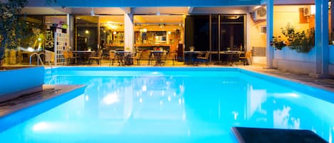 Una piscina al aire libre, sombrillas, sillones reclinables de piscina