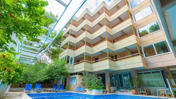 Een buitenzwembad, parasols bij het zwembad en ligstoelen