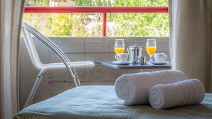Een balkon met een ontbijtje, inclusief een waterkoker, kopjes en glazen jus d'orange.
