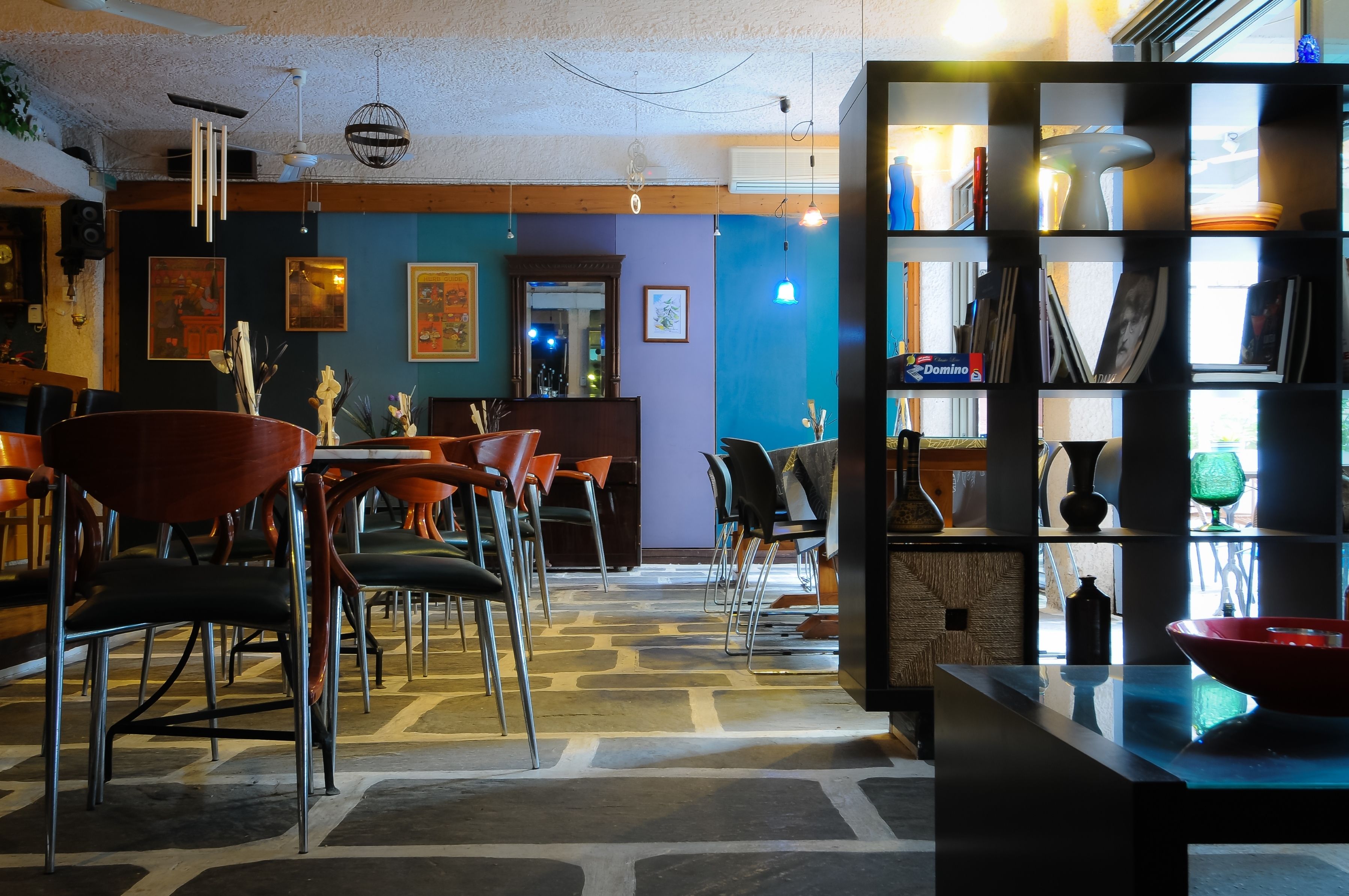 A restaurant interior with a central dining area, a bar, and a bookshelf.