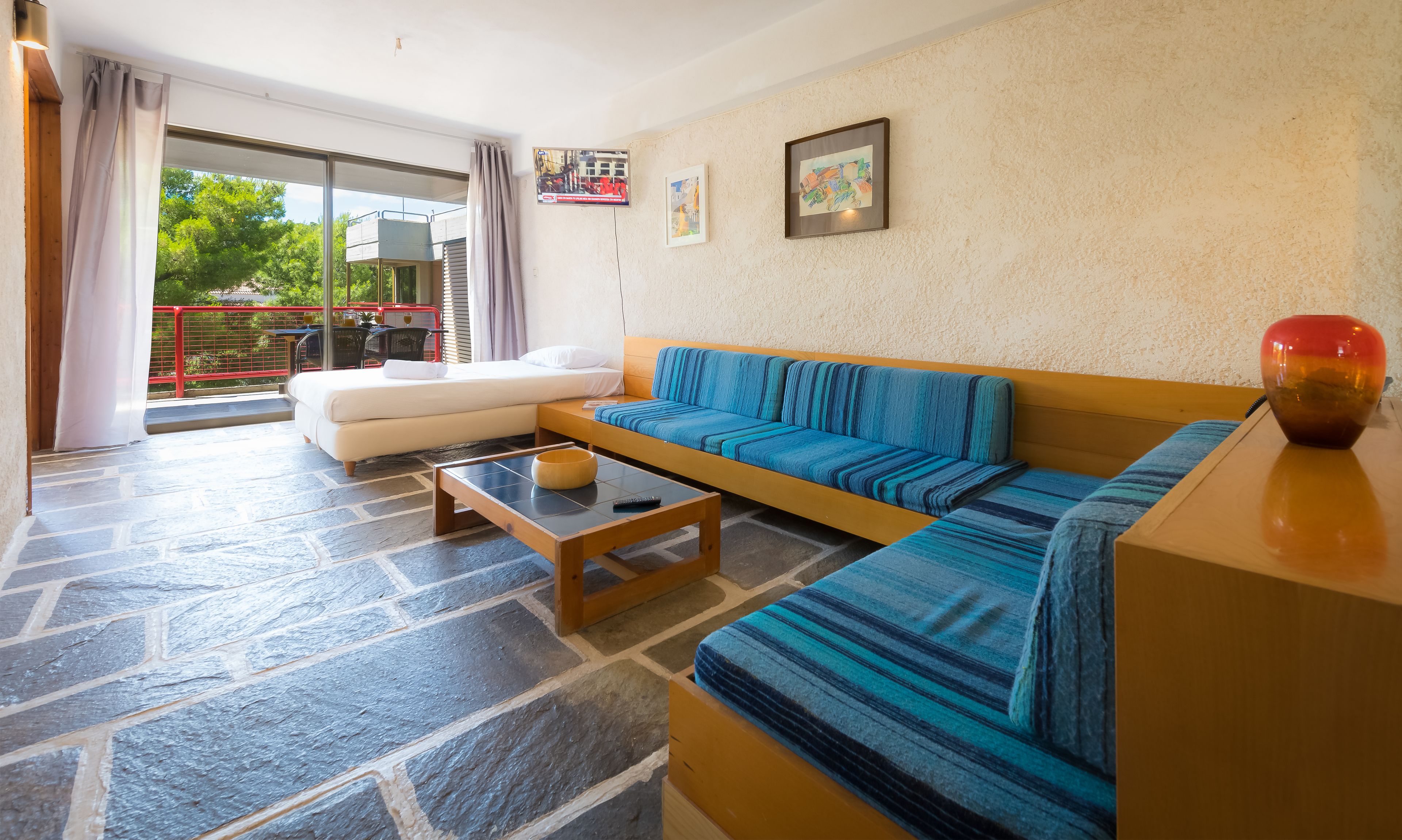 Una sala de estar moderna con un sofá, una mesa de centro y una cama. Hay un balcón con una mesa y sillas afuera.