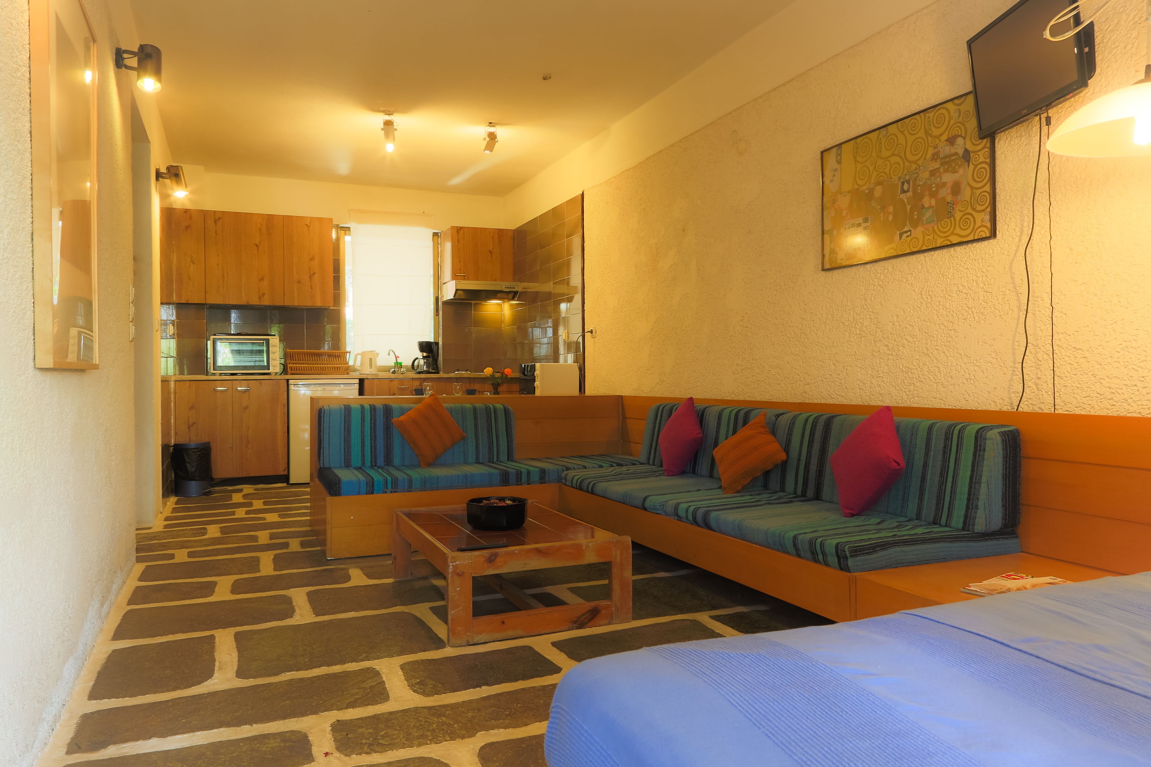A compact living space with a kitchenette, a sofa set, a coffee table, and a bed.