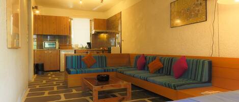 A compact living space with a kitchenette, a sofa set, a coffee table, and a bed.