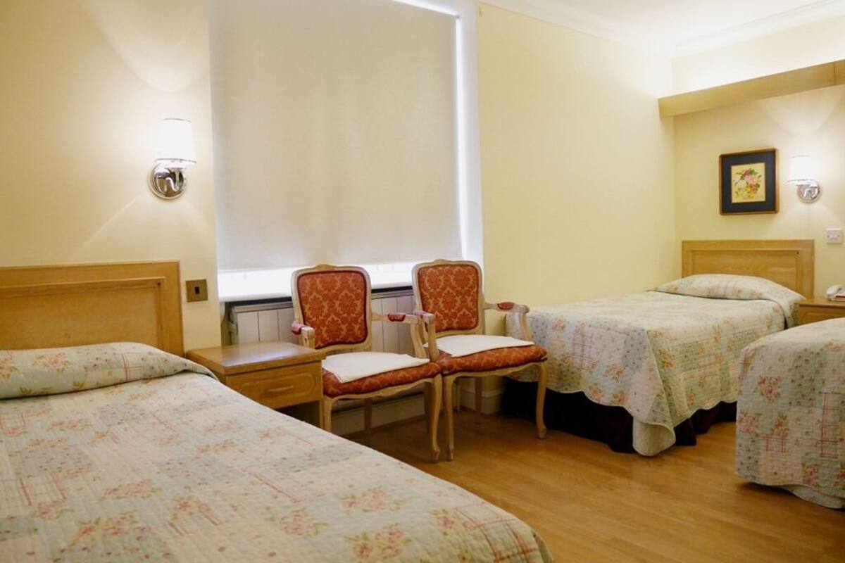 Una habitación de hotel con dos camas, una silla y una mesita.