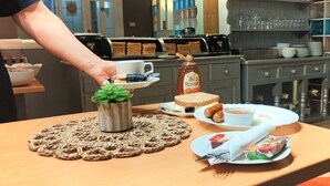 Une table dressée pour le petit-déjeuner avec un croissant, du miel, de la confiture et une petite plante.
