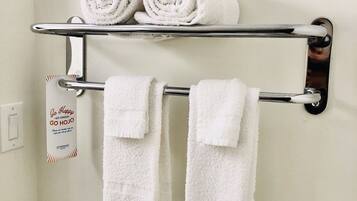 A bathroom with a towel rack holding two rolled towels and two folded towels.