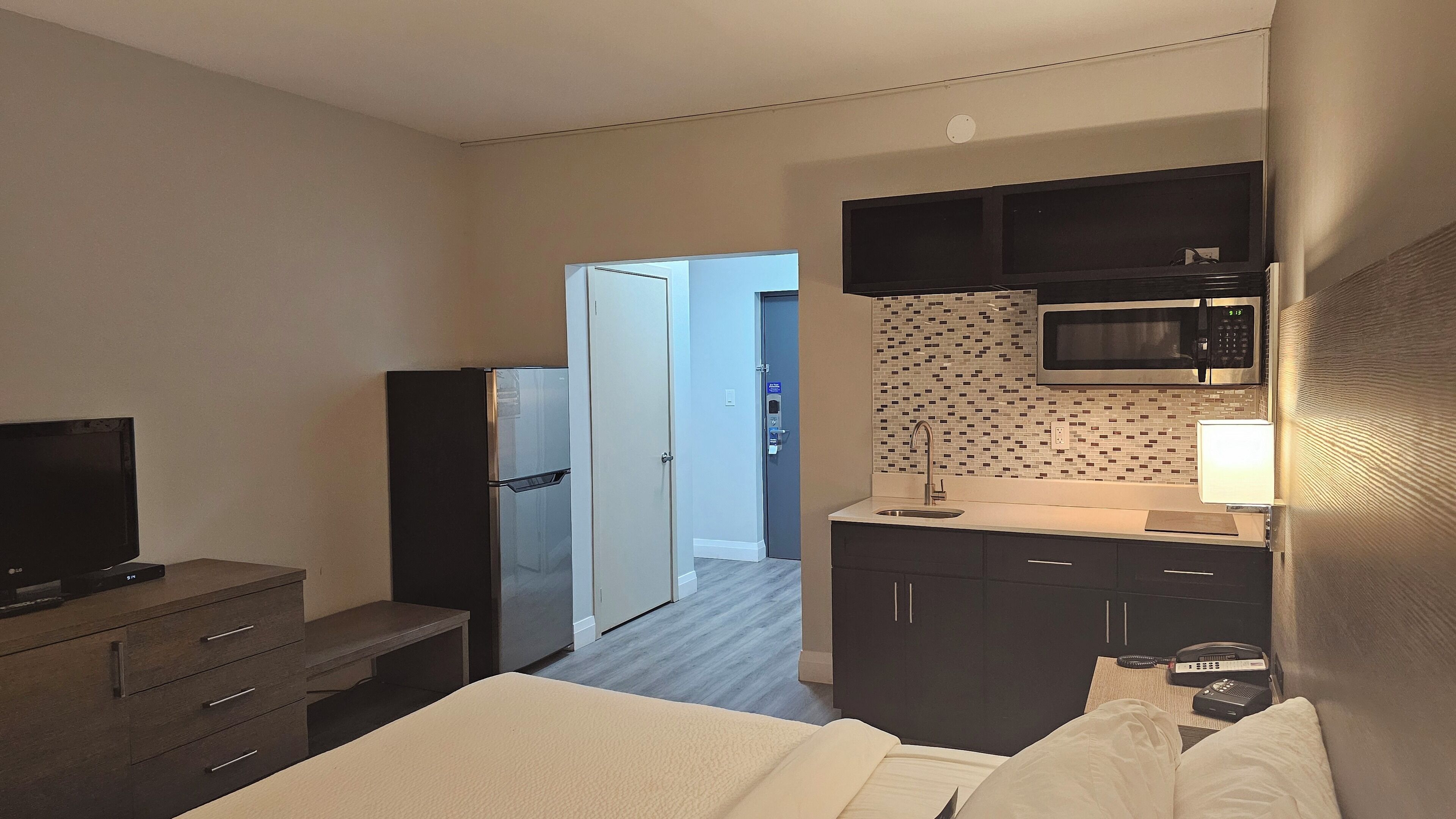 Une chambre d’hôtel équipée d’un lit, d’une télévision, d’un réfrigérateur, d’un four à micro-ondes, d’un lavabo et d’une armoire.