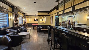 A bar area with leather chairs, a pool table, and a bar counter with glasses and bottles. - Super 8 by Wyndham Kirkland Lake (Kirkland Lake)