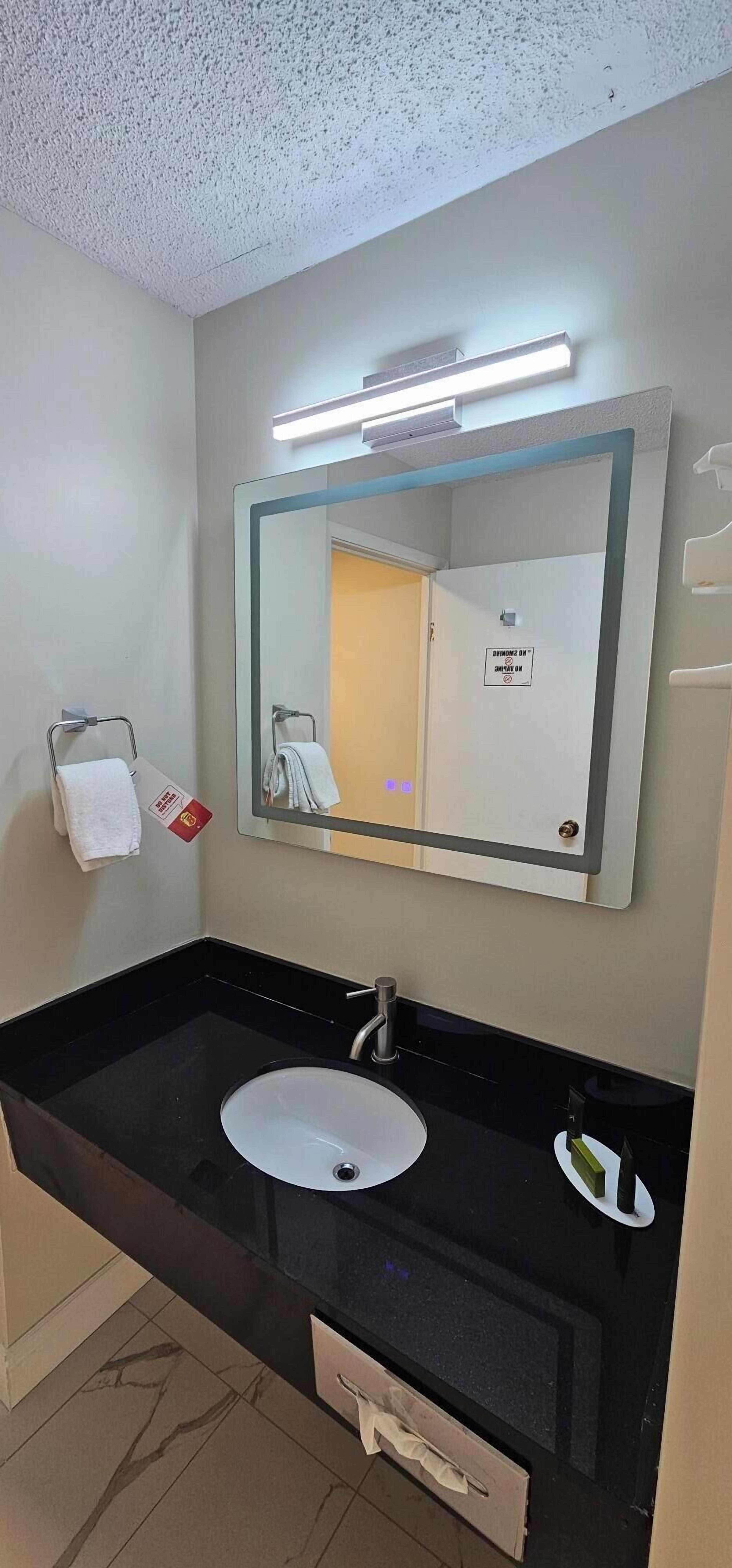 A bathroom with a black sink, a large mirror, and a towel rack.