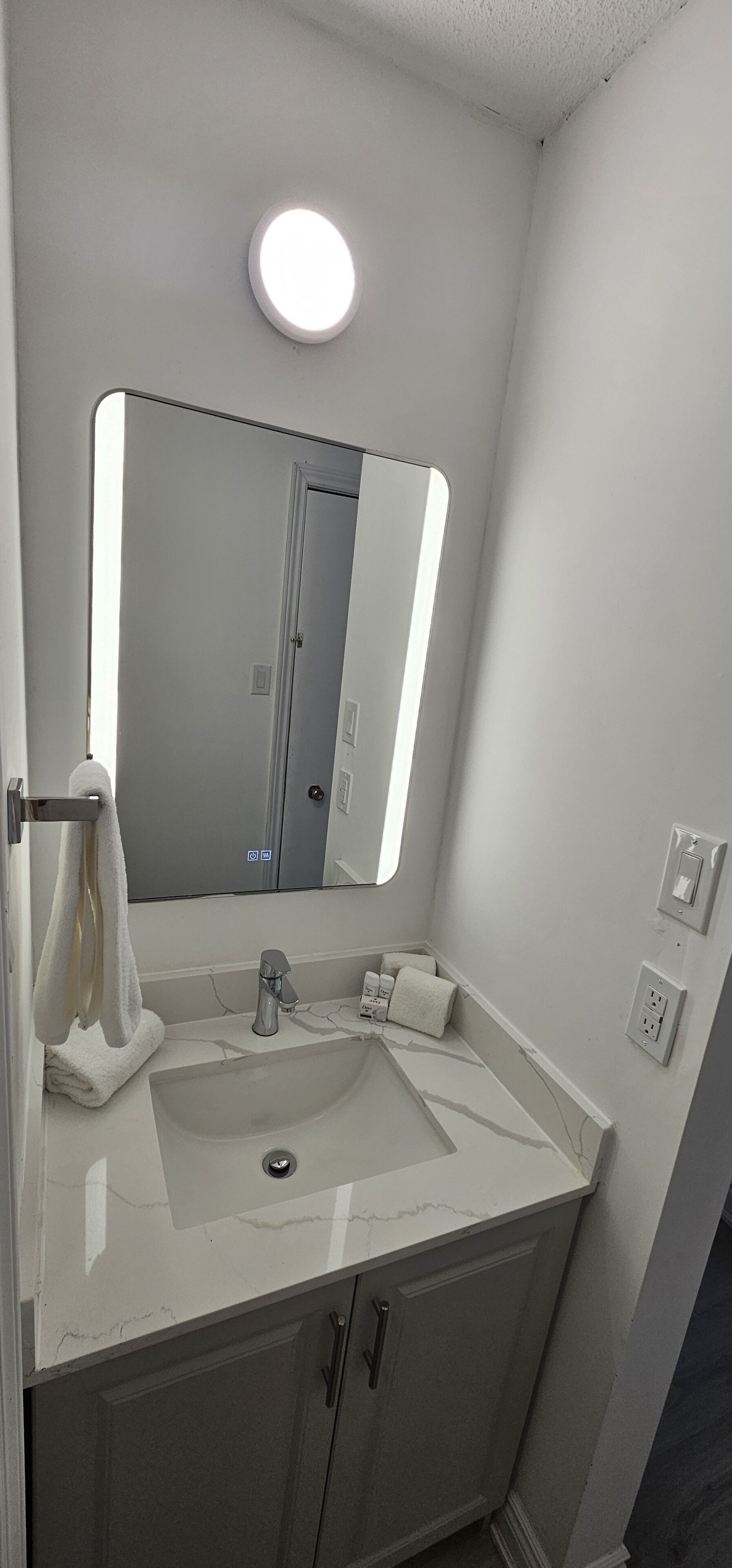 A bathroom with a white sink, a mirror, and a towel rack.