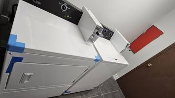 A white washing machine with a control panel, blue tape on the side, and a red door in the background.