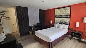 A hotel room with a bed, bedside tables, a desk, a chair, a wardrobe, and a large painting on the wall. - Super 8 by Wyndham Kirkland Lake (Kirkland Lake)
