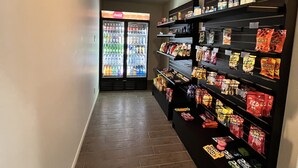 A hallway with a vending machine stocked with snacks and a Coca-Cola refrigerator. - Super 8 by Wyndham Kirkland Lake (Kirkland Lake)