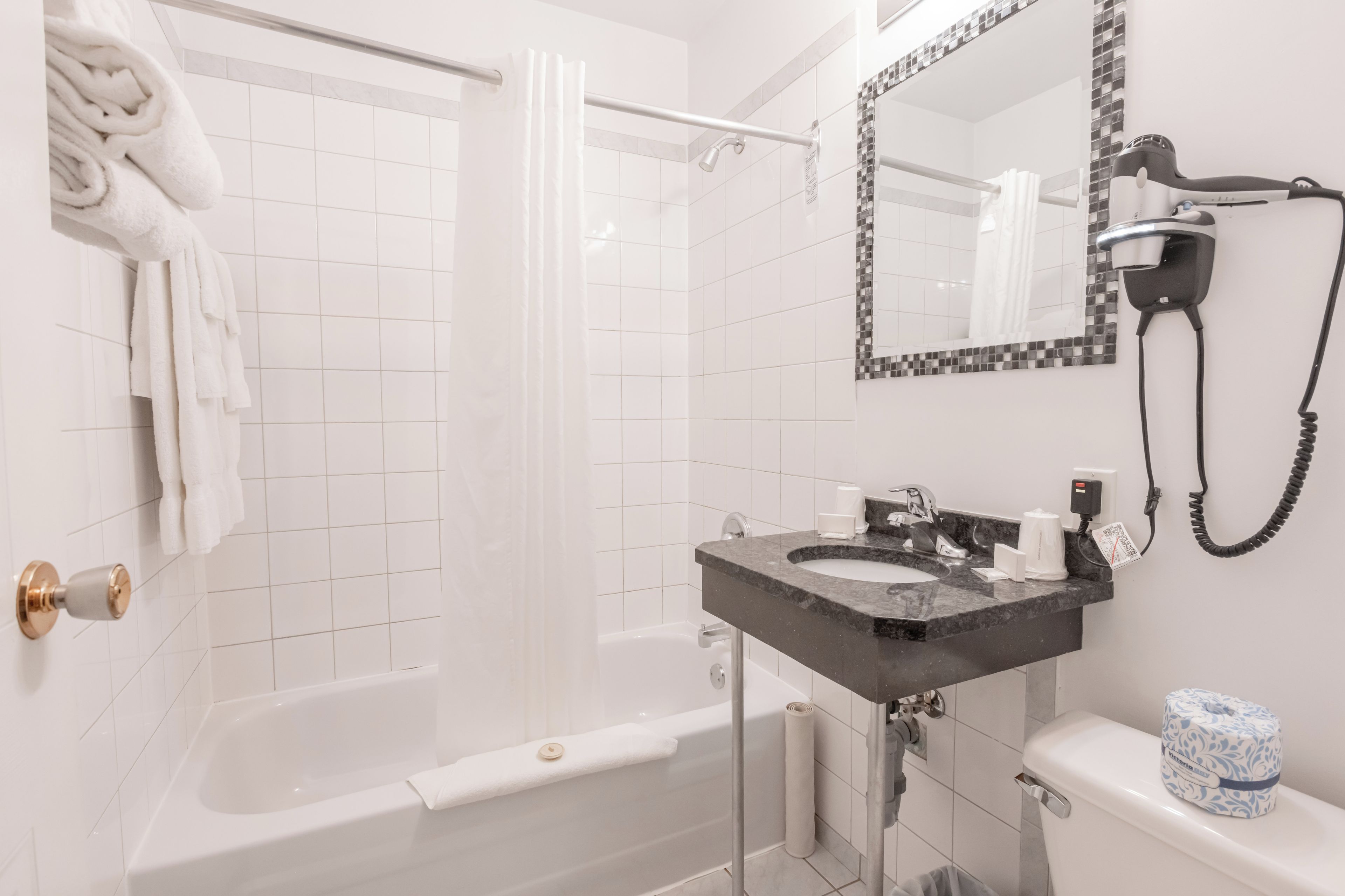 Een badkamer met een bad, een douche, een wastafel met spiegel en een toilet.