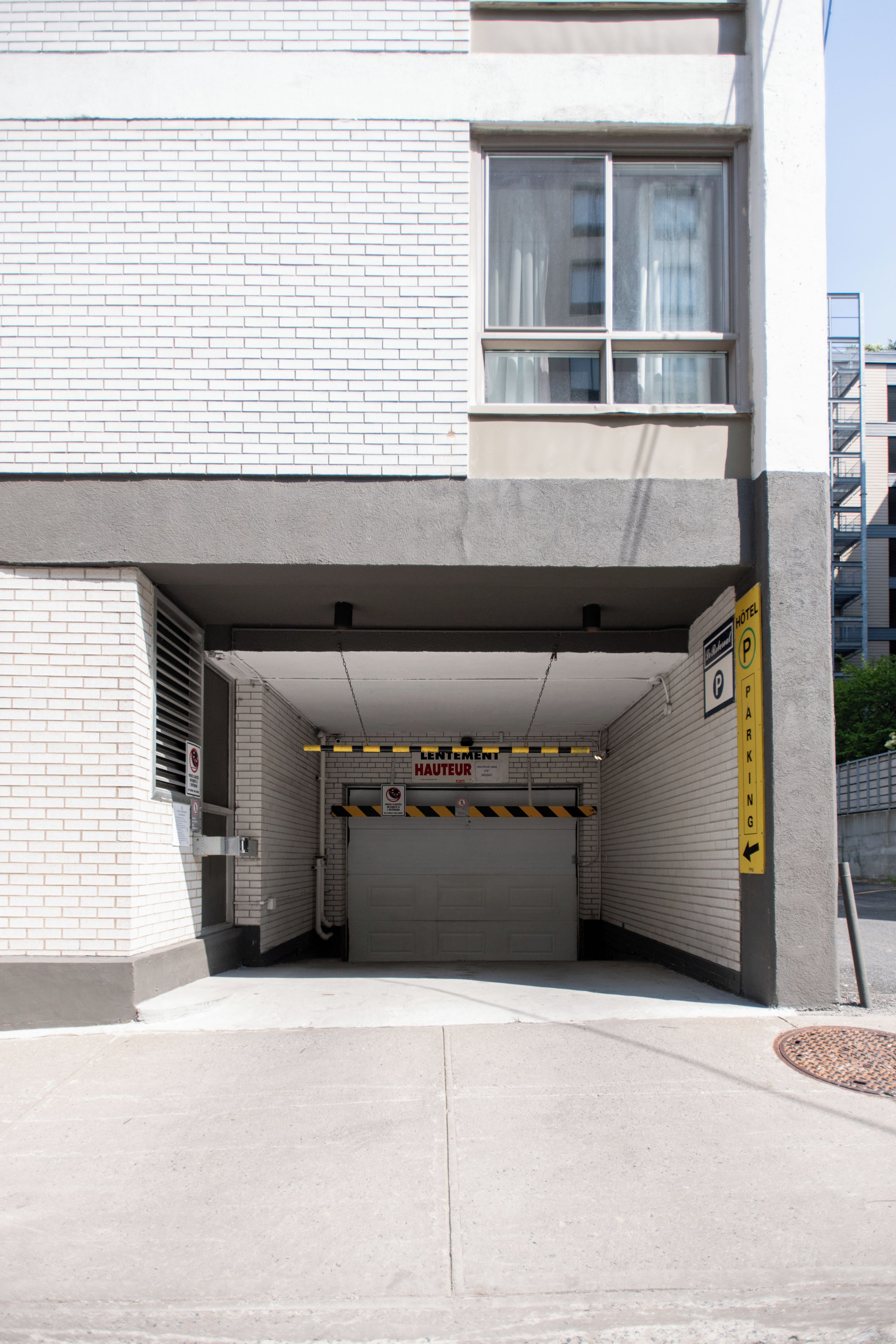 A hotel entrance with a garage door, a no parking sign, and a caution sign for height.