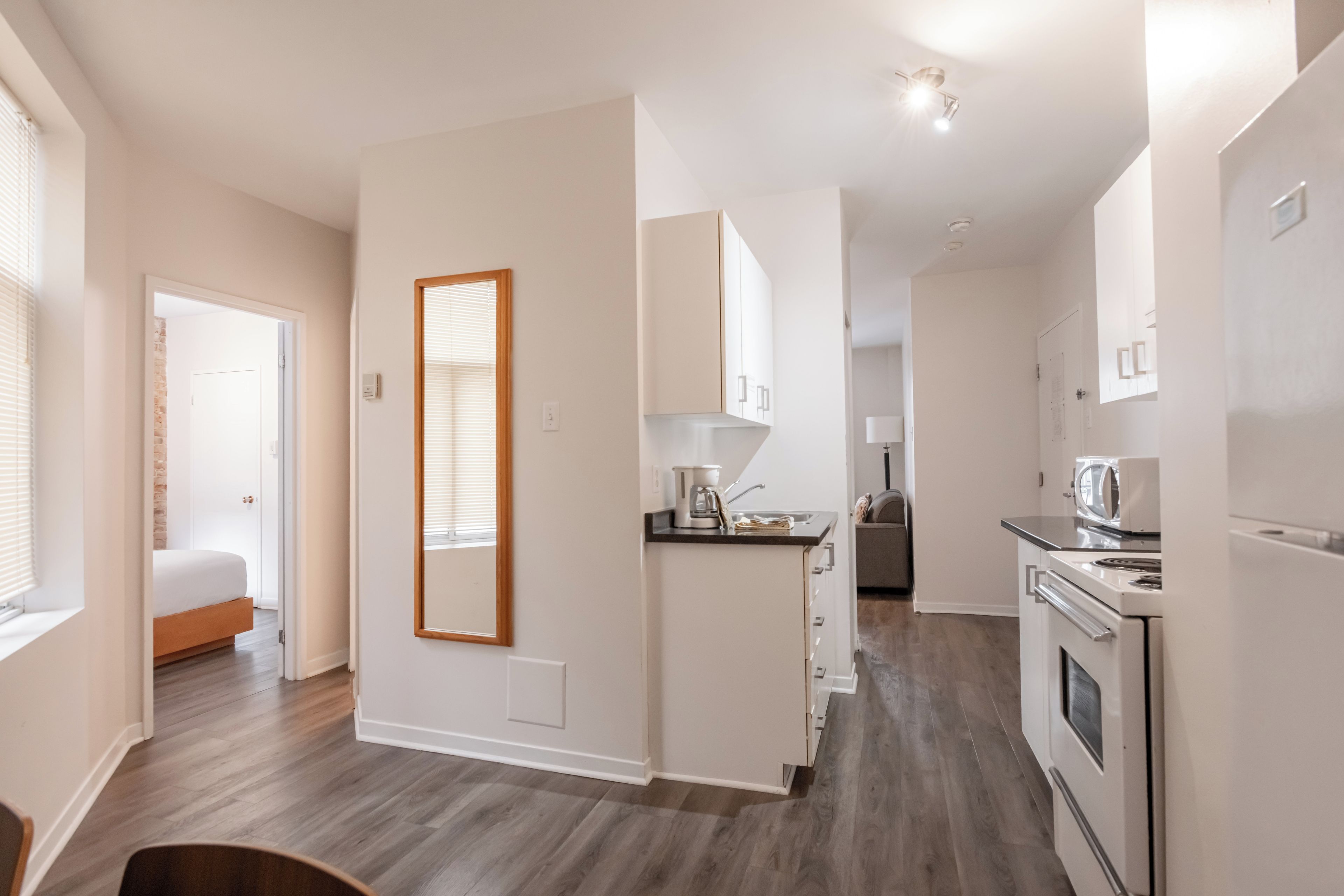 A modern apartment with a kitchen, dining area, and a bedroom.