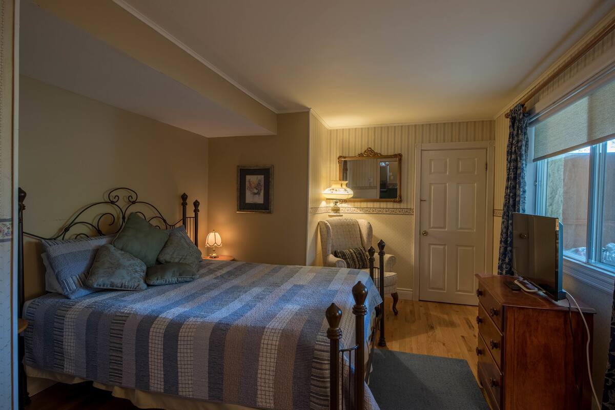 Ein Schlafzimmer mit einem Bett, einem Sessel, einer Kommode und einem Fernseher.