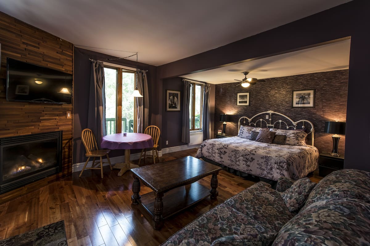 Ein gemütliches Schlafzimmer mit Bett, einer Couch, einem Tisch und einem Kamin.