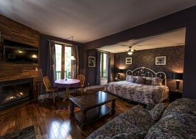 Une chambre confortable avec un lit, un canapé, une table et une cheminée.