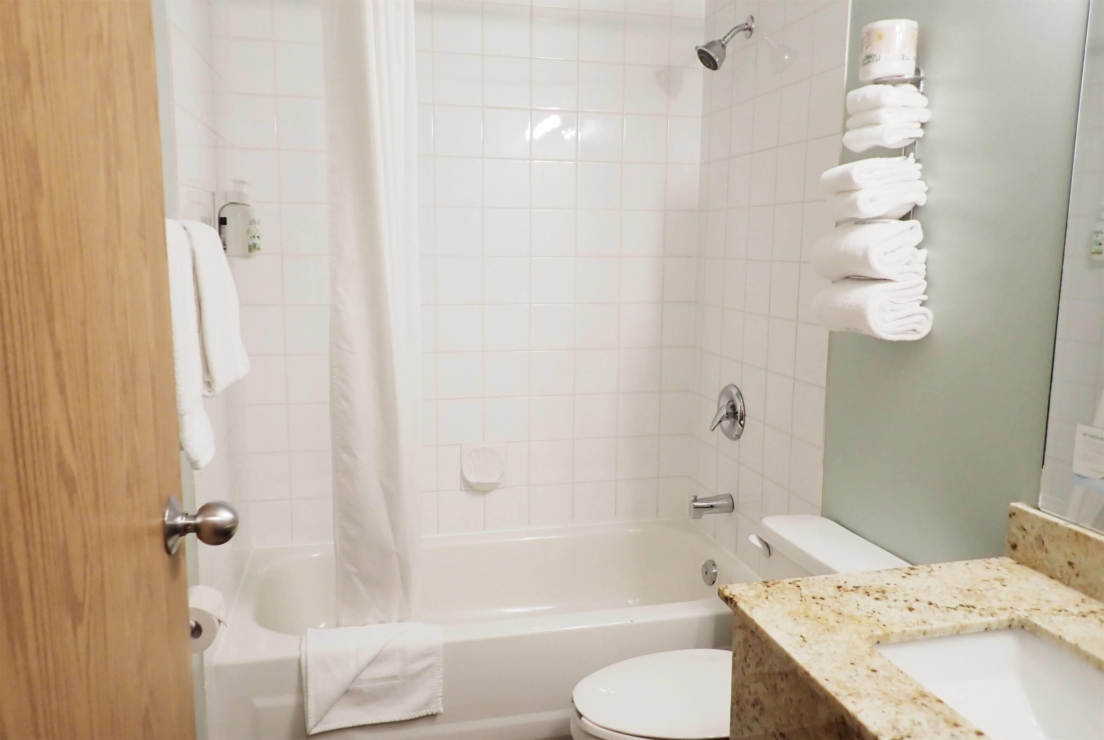 Un baño con bañera, inodoro y lavamanos con encimera de mármol.