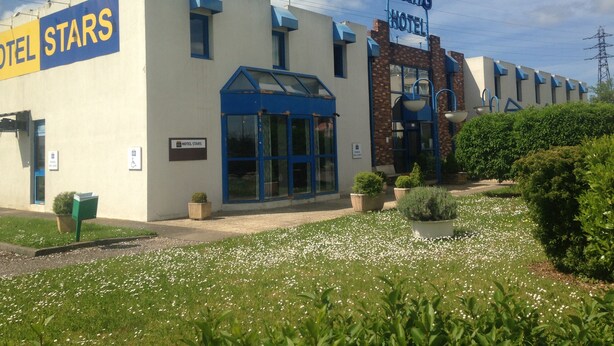 Un hotel llamado 'Hotel Stars' con diseño moderno, destacando una paleta de colores azul y blanco, una entrada imponente y un jardín bien cuidado.