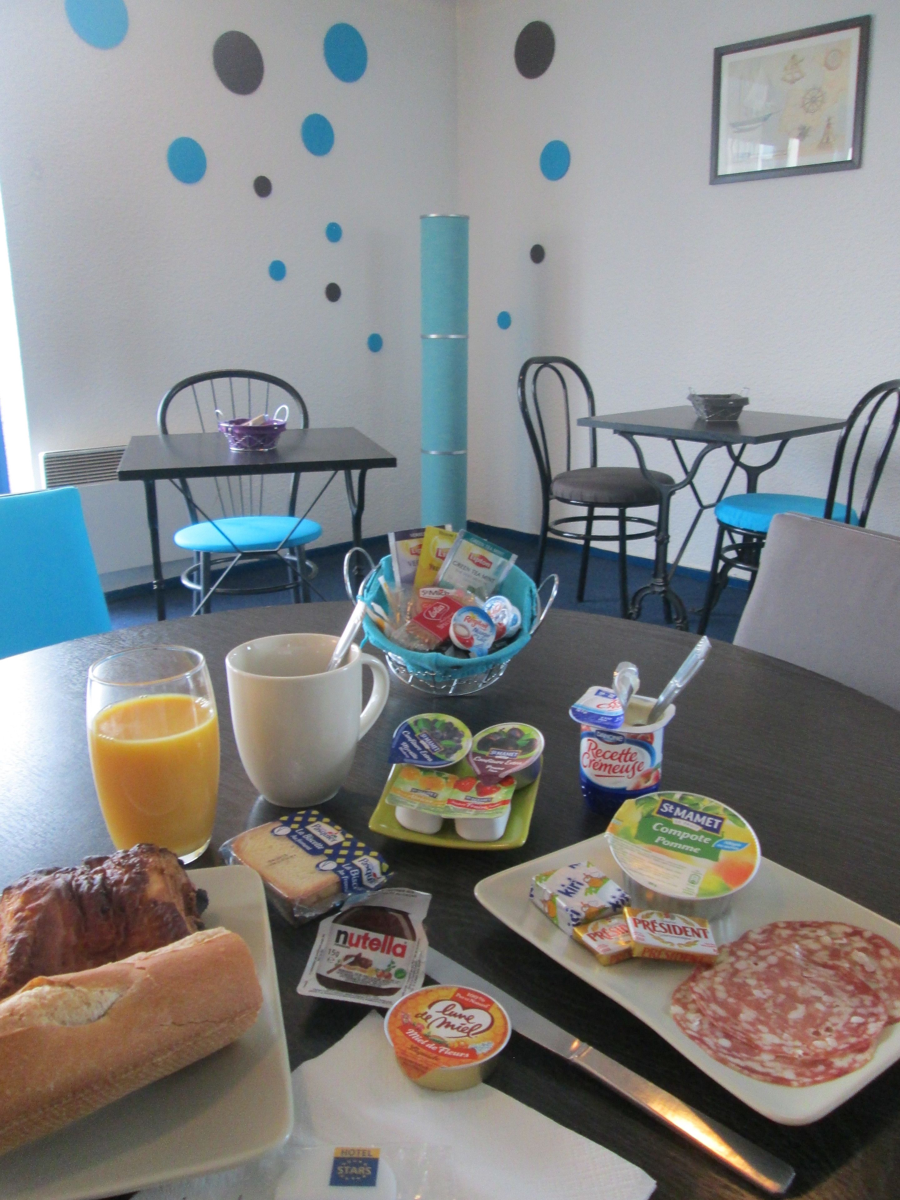 A breakfast table with various food items, a coffee cup, and a juice glass.