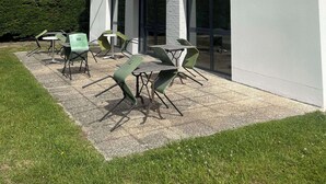 A modern building with a flat roof, large windows, and a patio area with outdoor seating. - Kyriad Direct Dreux (Dreux)