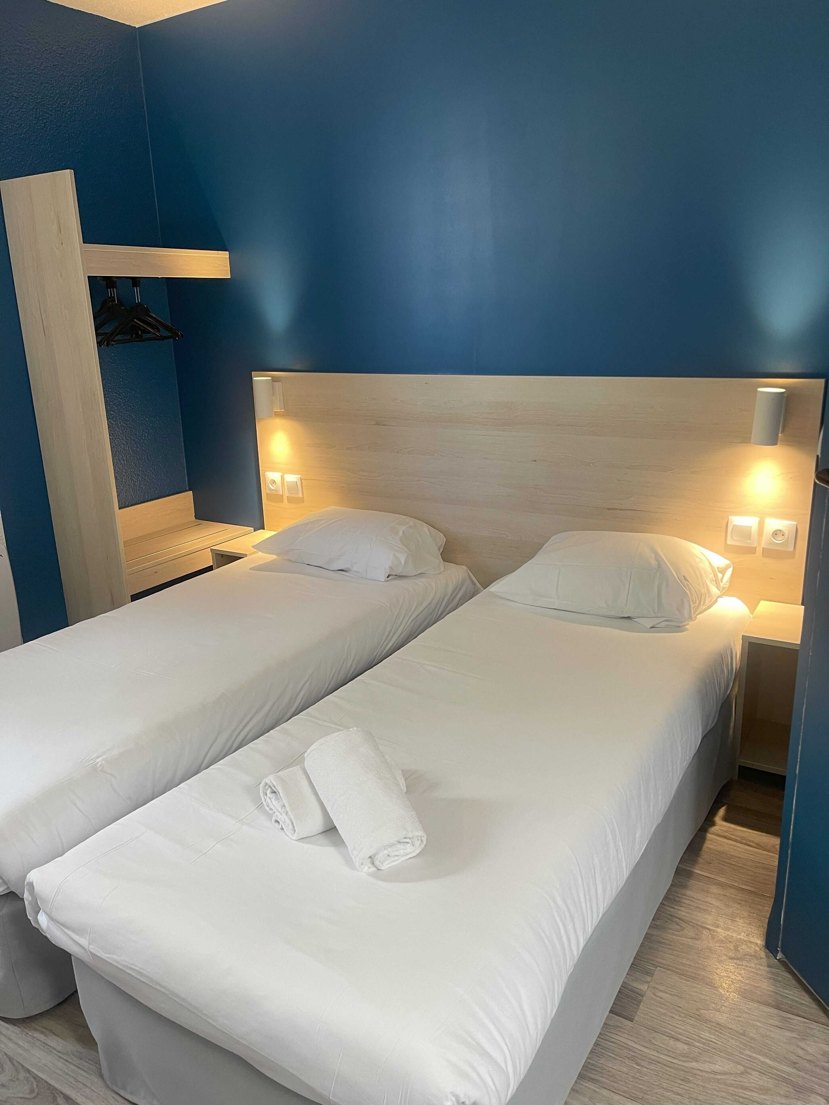 A hotel room with two single beds, a wooden headboard, and bedside lamps.