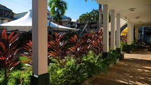 A covered outdoor area with a pathway, surrounded by lush greenery and palm trees. - Village Creole (Trois-Ilets)