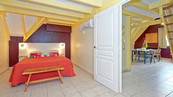 A bedroom with a bed, bedside tables, and a nightstand. There is a door leading to another room.