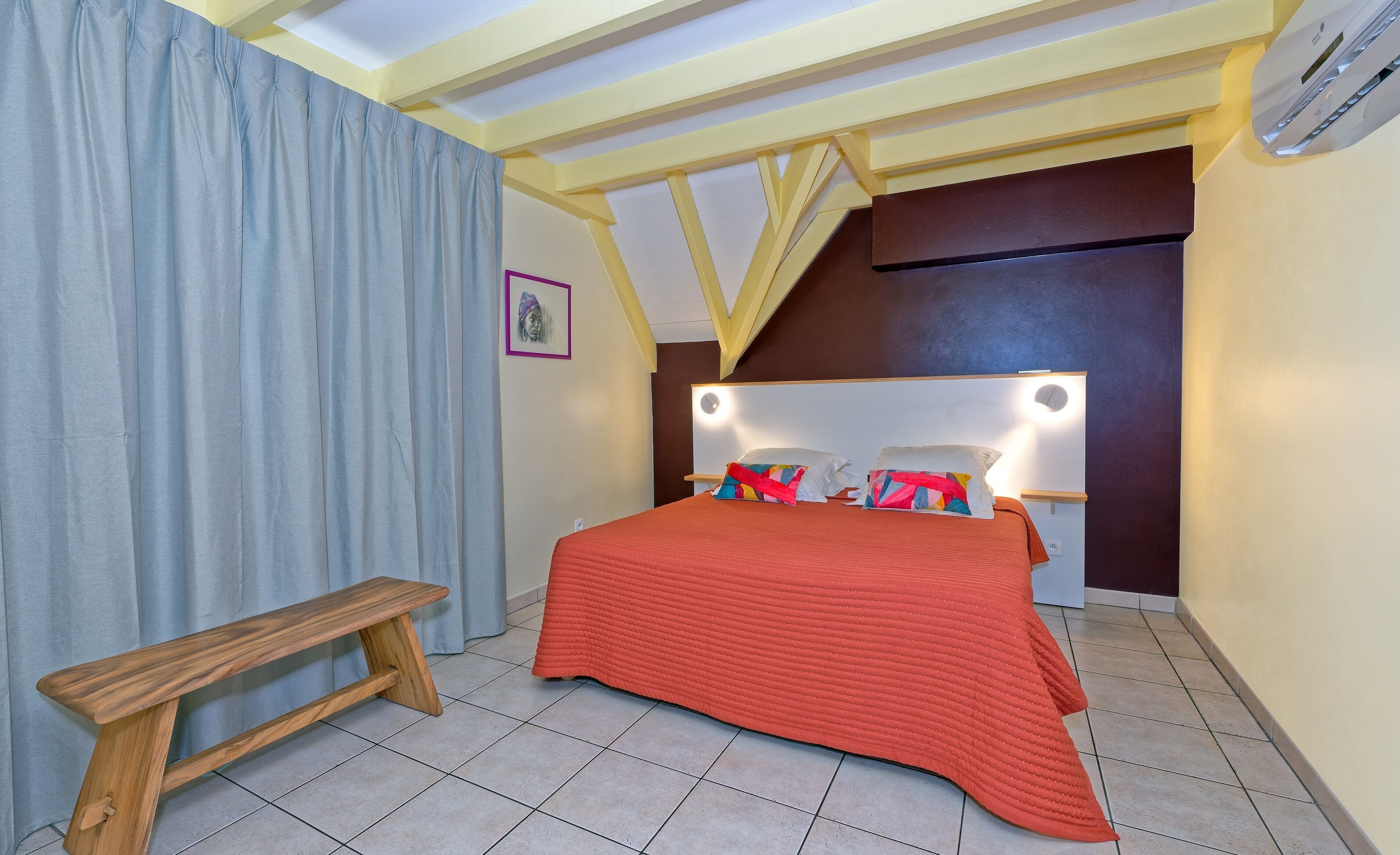 A bedroom with a bed, bench, and a headboard with lights.