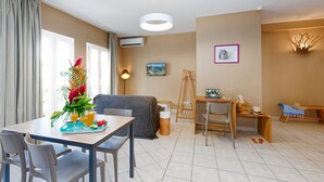 A modern living room with a dining area, a grey sofa, a wooden coffee table, and a painting on the wall. - Village Creole (Trois-Ilets)