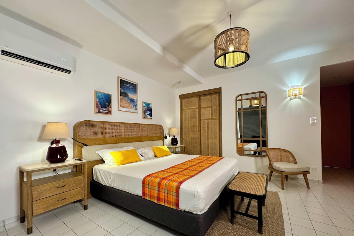 A bedroom with a bed, bedside tables, a chair, a mirror, and wall-mounted lights.