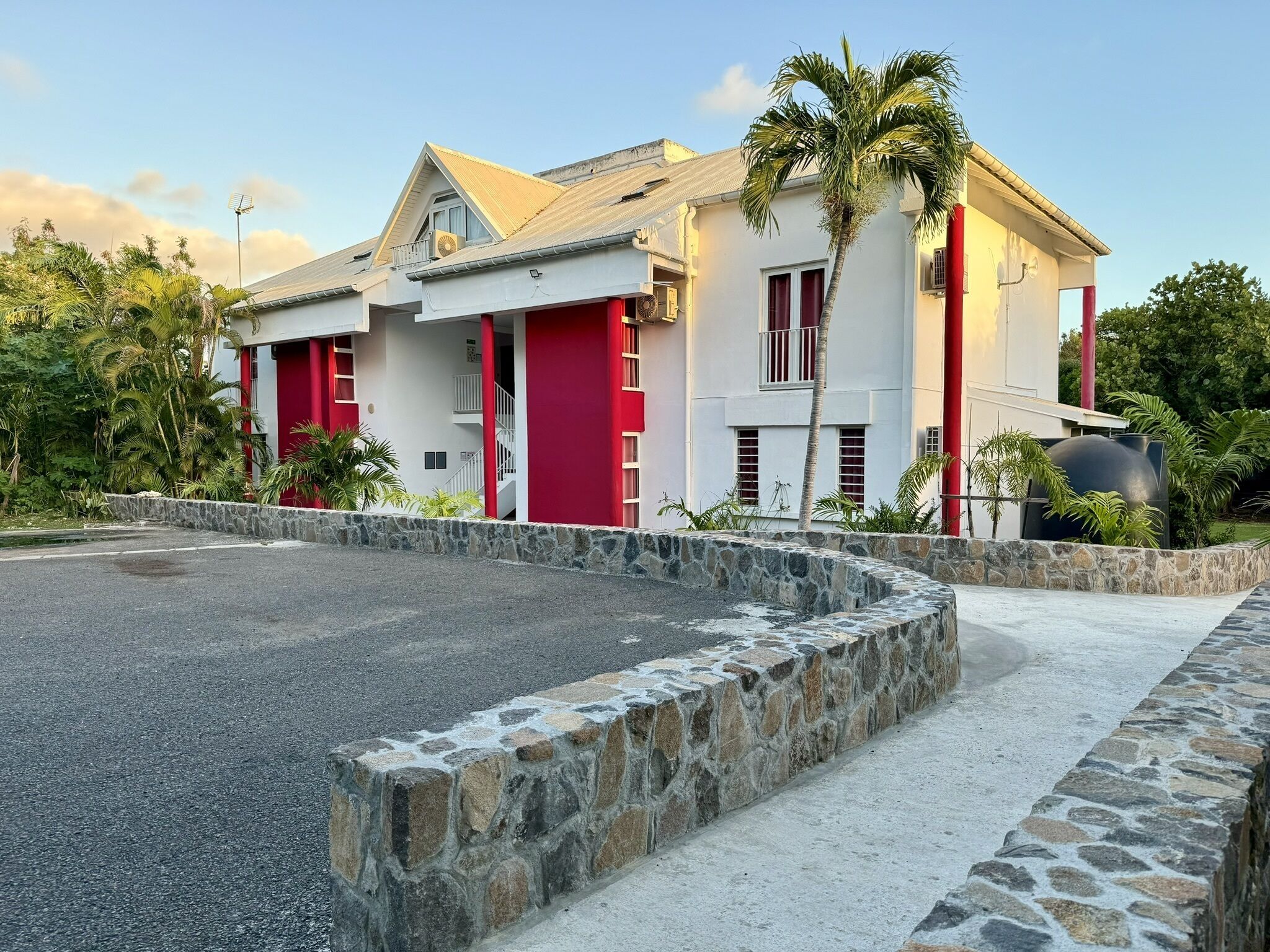 A two-story building with a stone retaining wall in front.