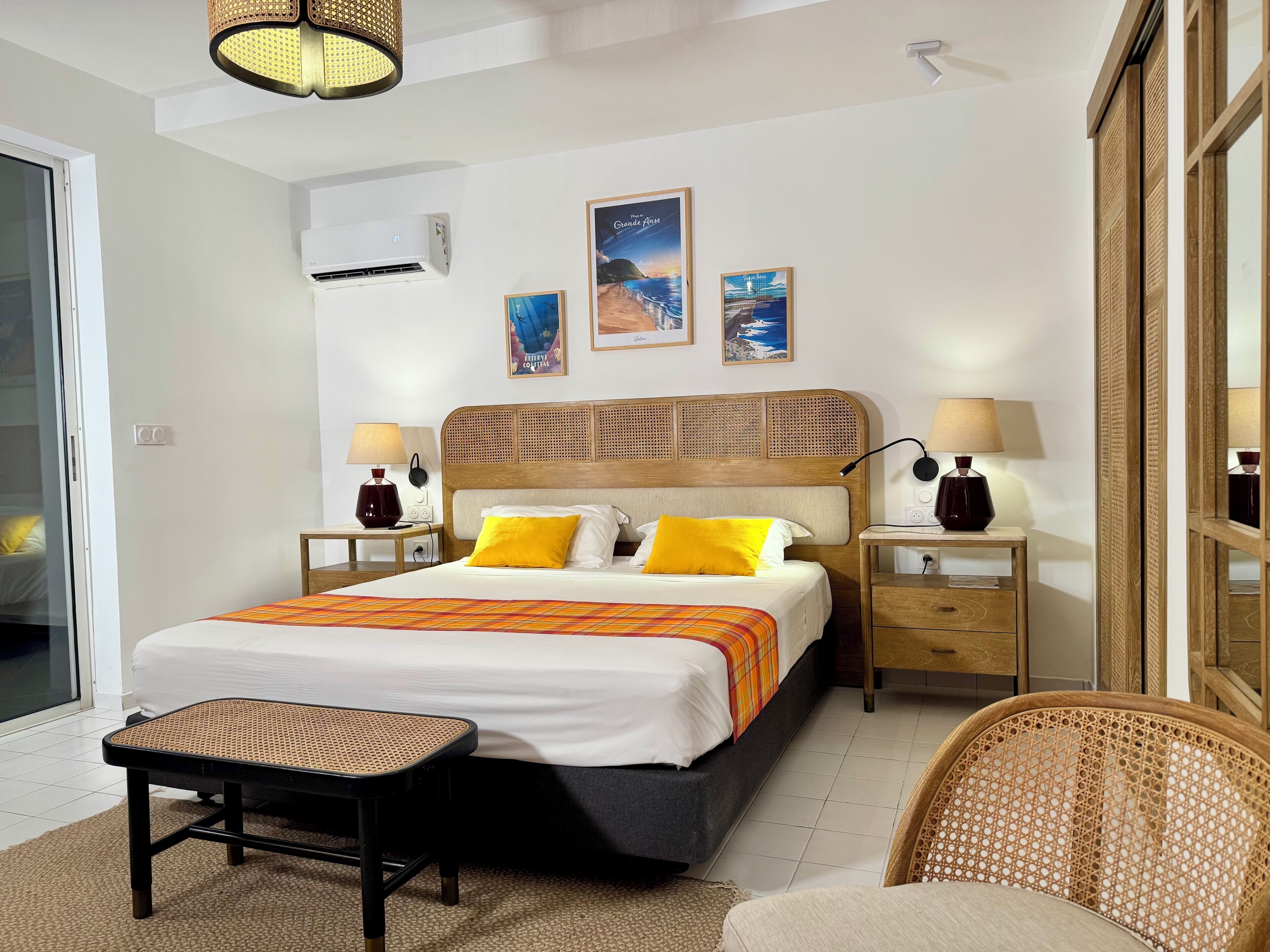 A hotel room with a bed, bedside tables, a chair, a small table, and a mirror.