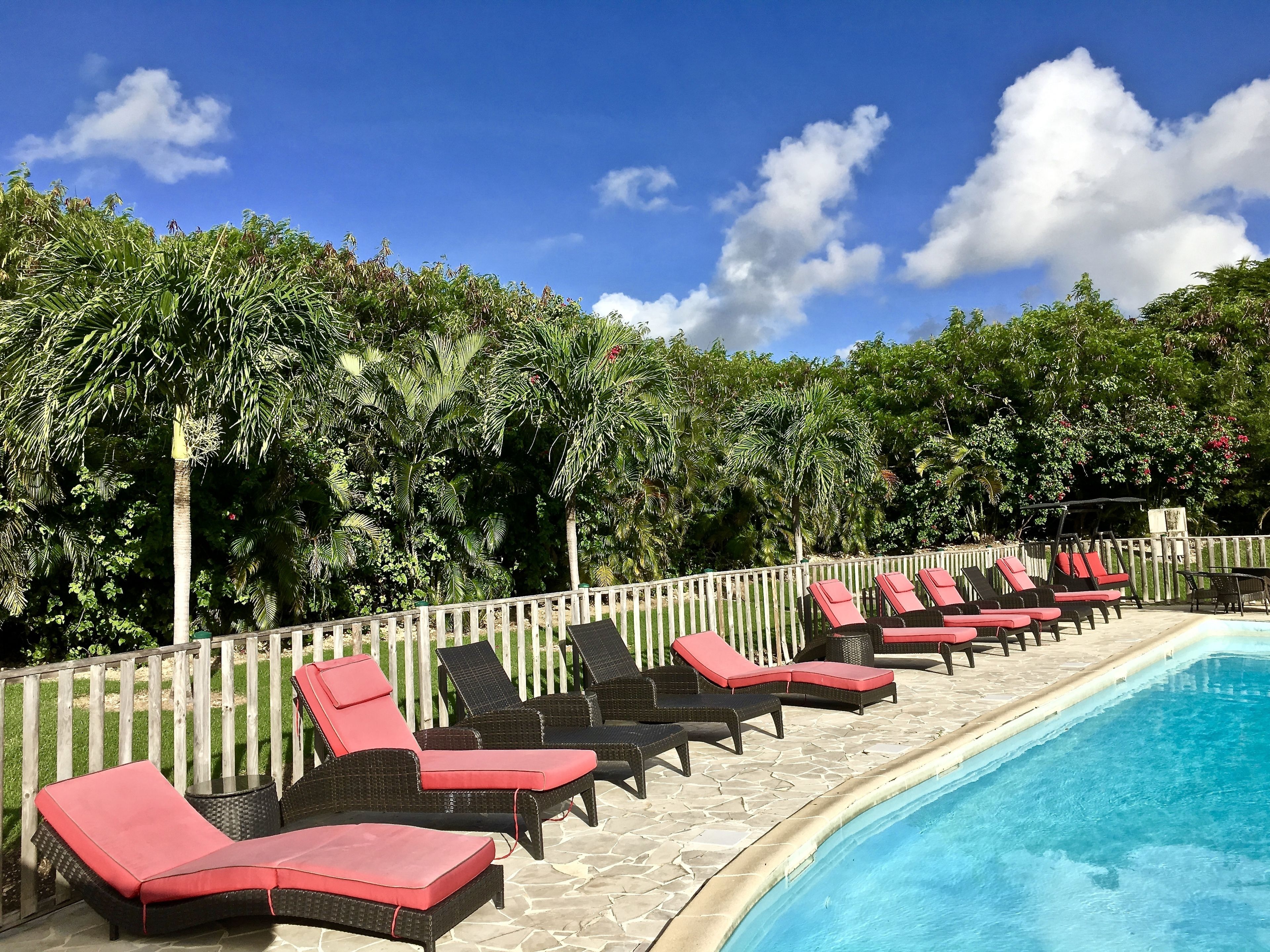 A poolside area with lounge chairs and a wooden fence.