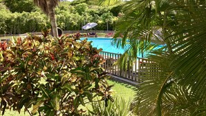 A swimming pool surrounded by lush greenery and palm trees. - Résidence Le Vallon Guadeloupe (Saint-François)