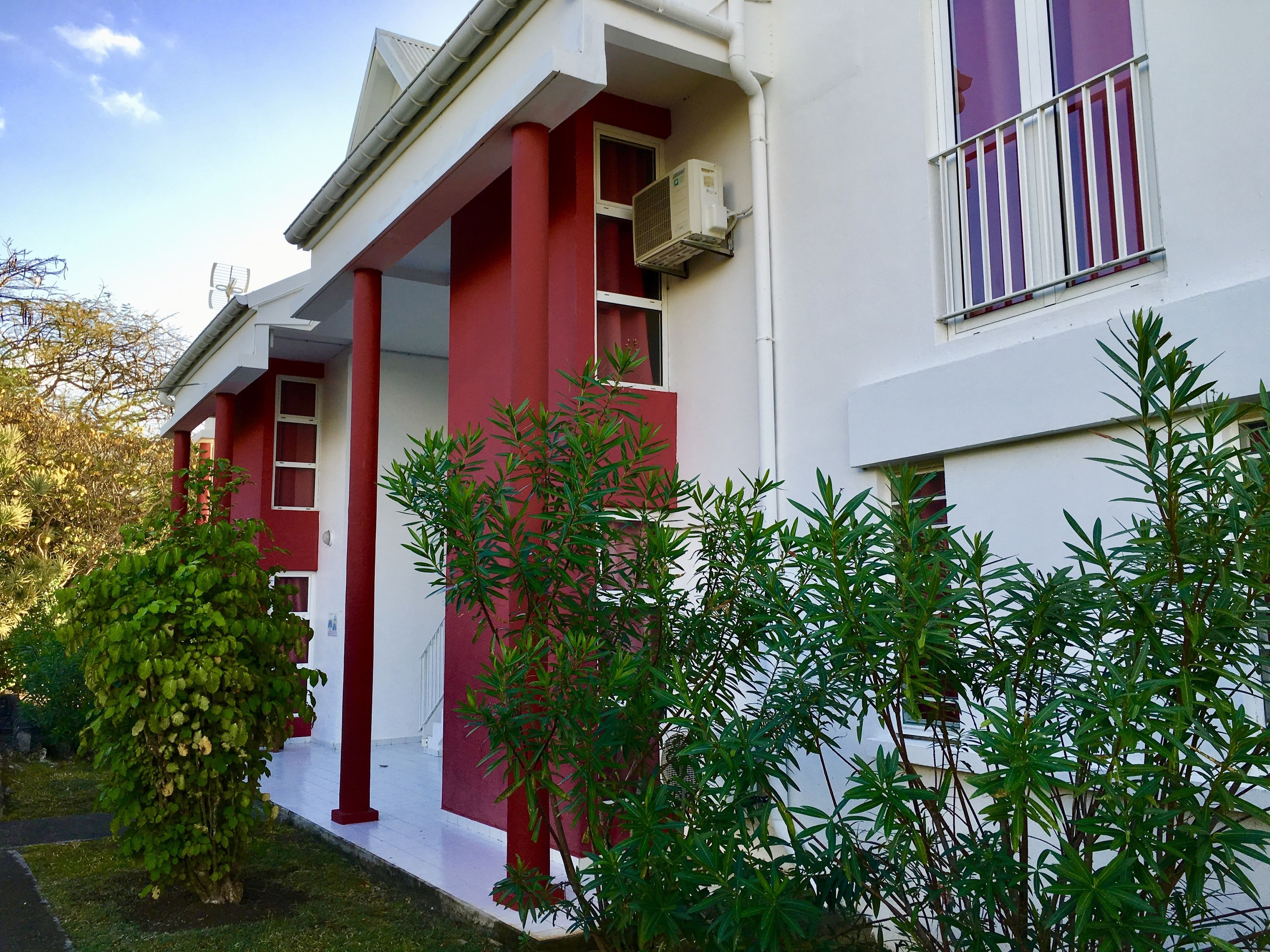 A modern building with a red and white facade, large windows, and a balcony.