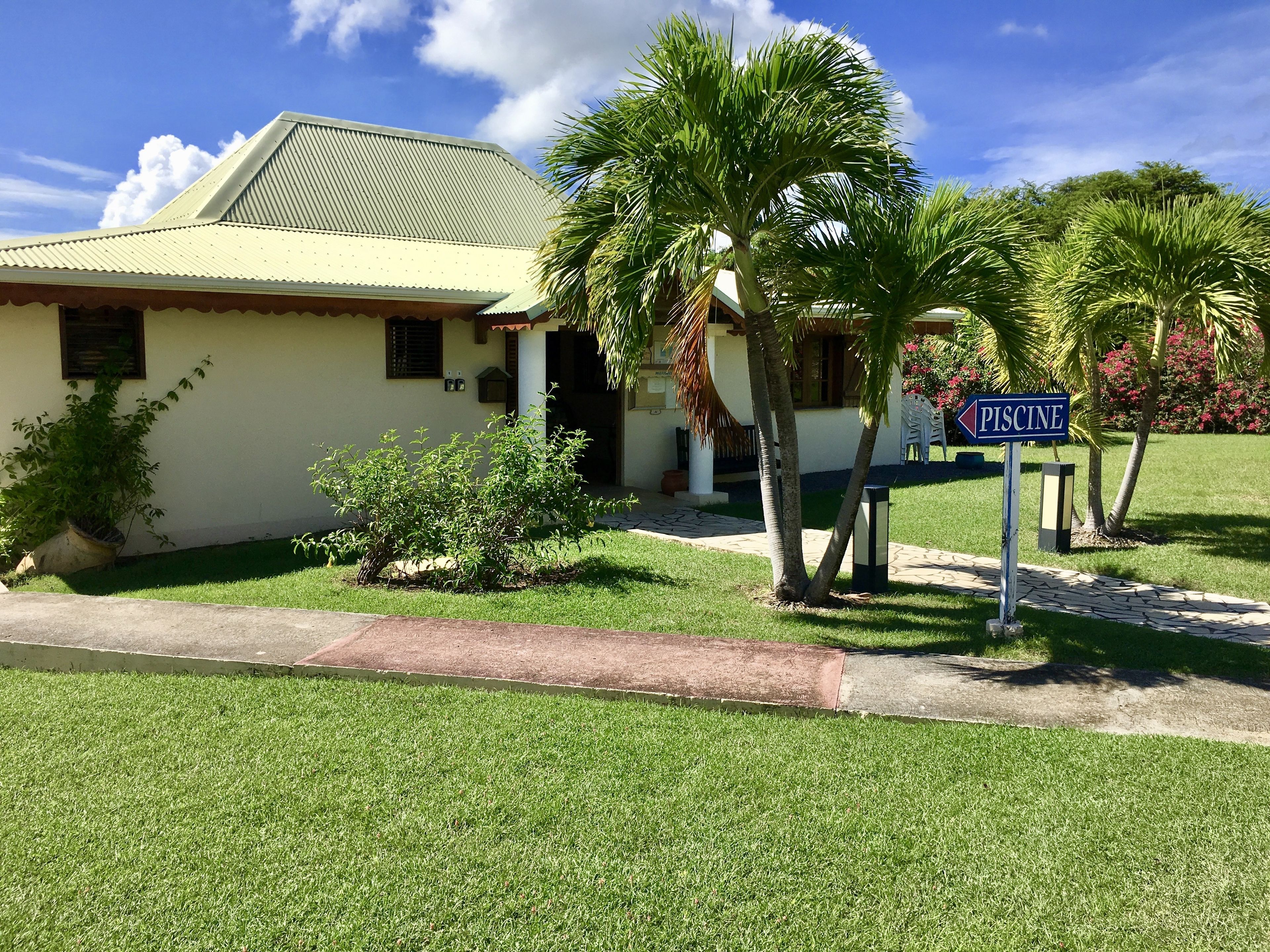 A house with a sign indicating a 'PISCINE' nearby.