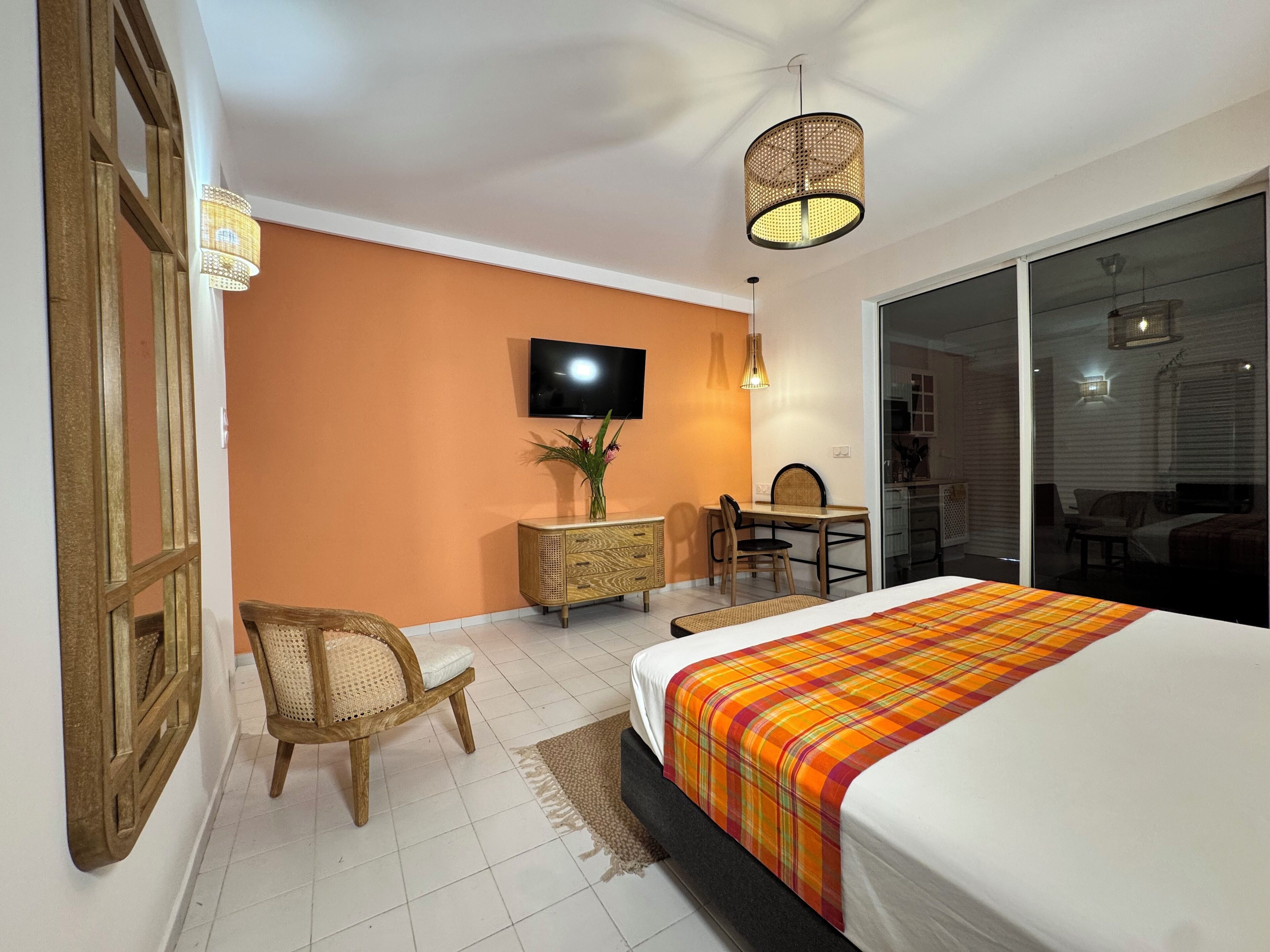 Een hotelkamer met een bed, een bureau, een stoel, een televisie en een groot raam.
