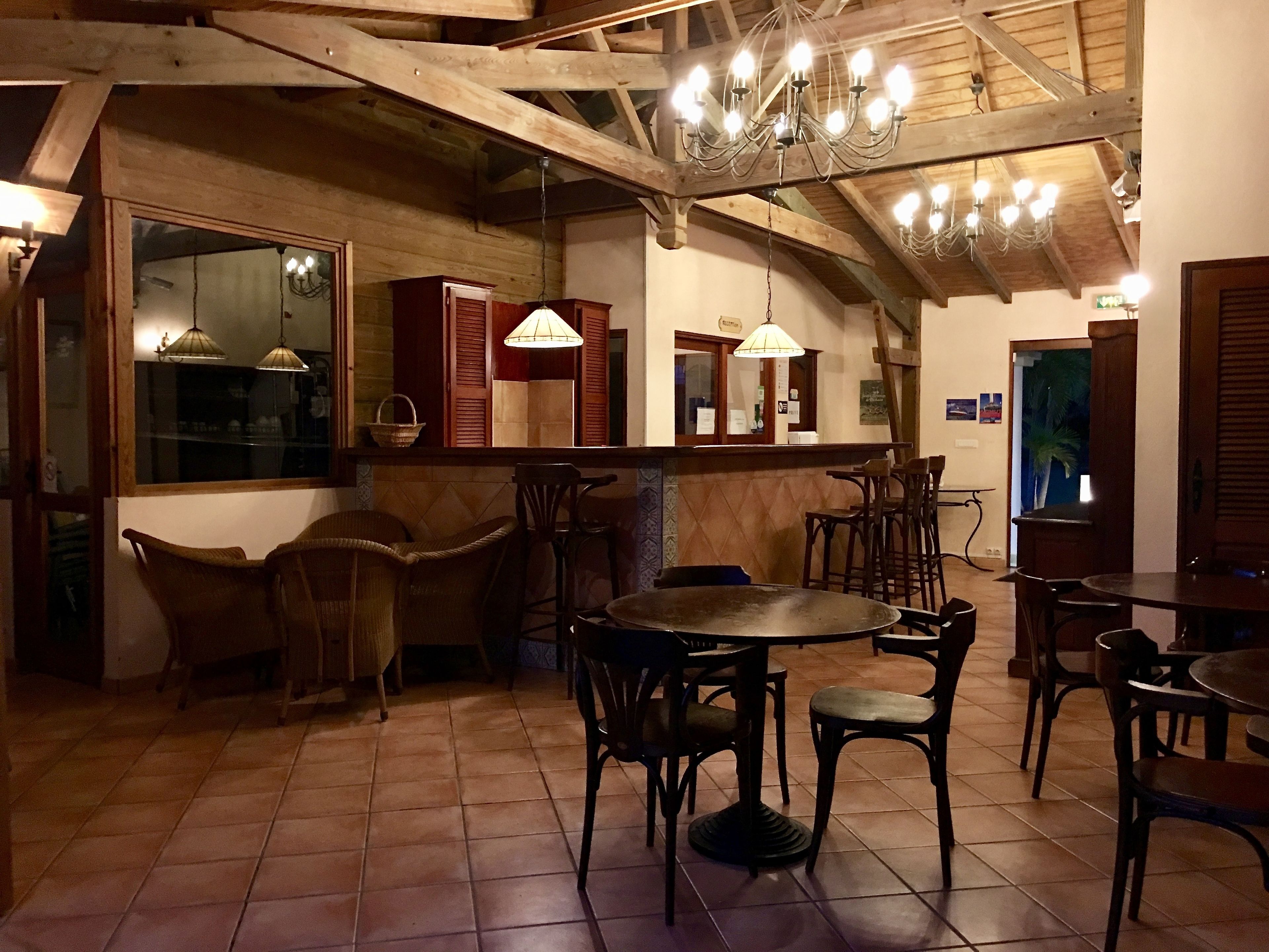 A rustic interior with wooden beams, a chandelier, and a tiled floor.