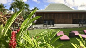 A building with a green roof, outdoor seating, and lush greenery. - Résidence Le Vallon Guadeloupe (Saint-François)