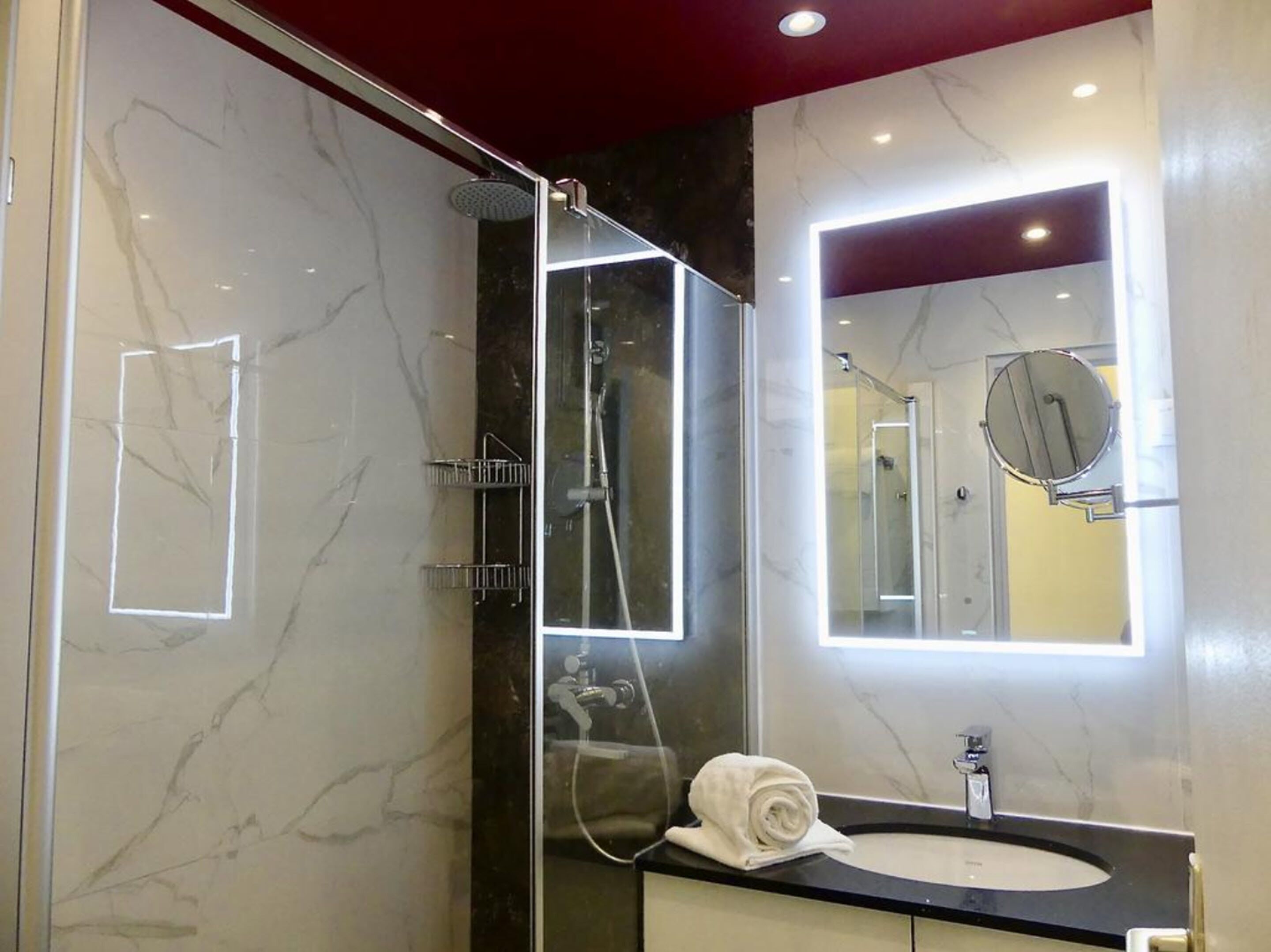 Un baño moderno con ducha envuelta en vidrio, tocador con espejo y toalla sobre la encimera.