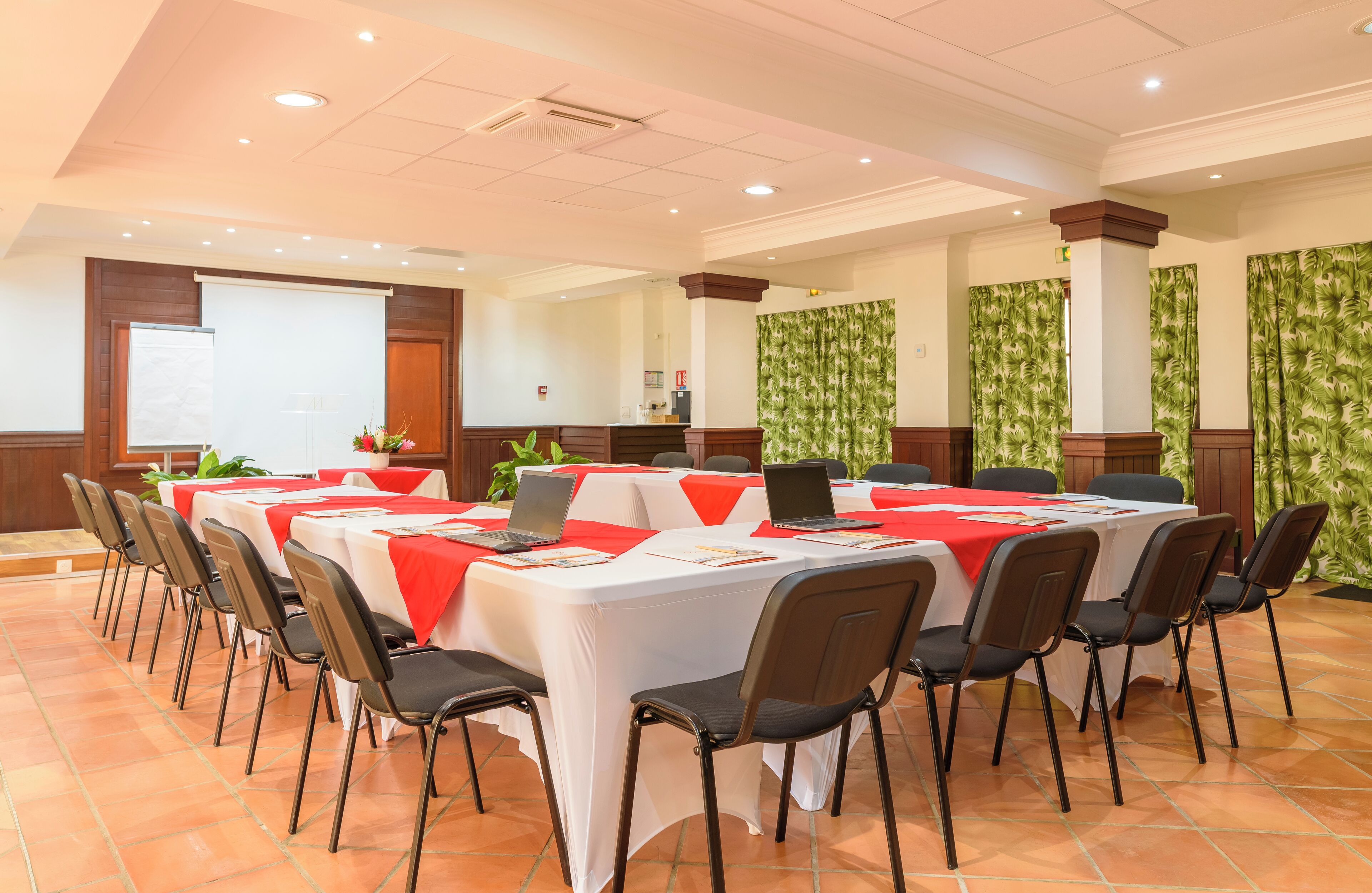 Una sala de conferències amb taules blanques, tovallons vermells i cadires negres.