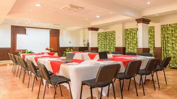Una sala de conferències amb taules blanques, tovallons vermells i cadires negres.