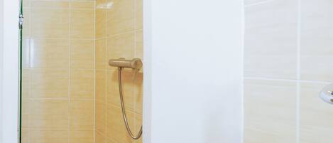 Un espacio de ducha pequeño y cerrado con azulejos amarillos y un lavamanos blanco.